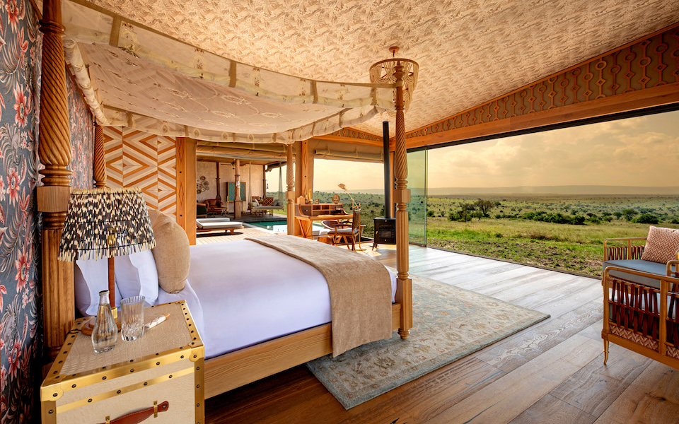 Luxury tented safari camp at dawn overlooking East African savannah with acacia trees and soft golden light